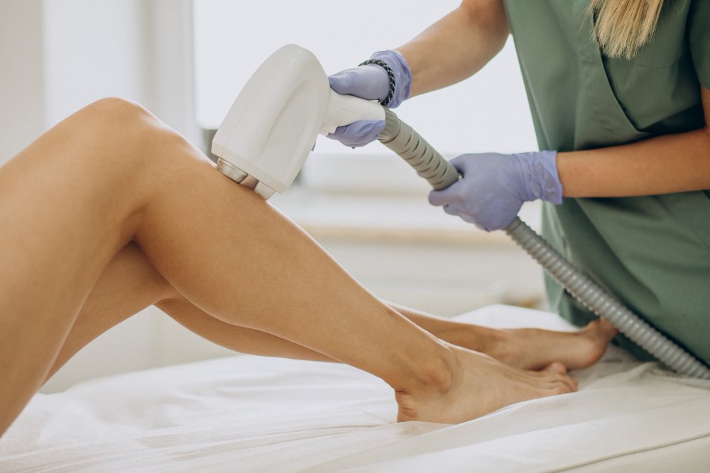 A hair removal specialist using a laser probe to remove hair from the client's leg