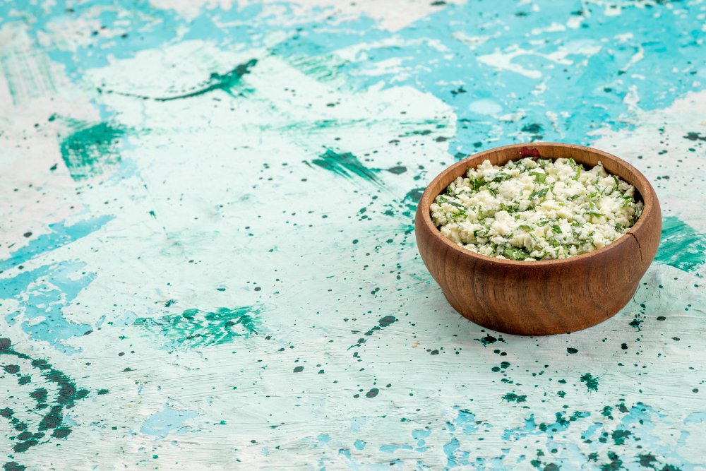 Celtic salt filled in a small clay bowl, placed on a rough surface with chipped blue paint