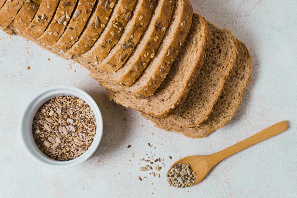 A sliced loaf of gluten-free bread with some grains on the side